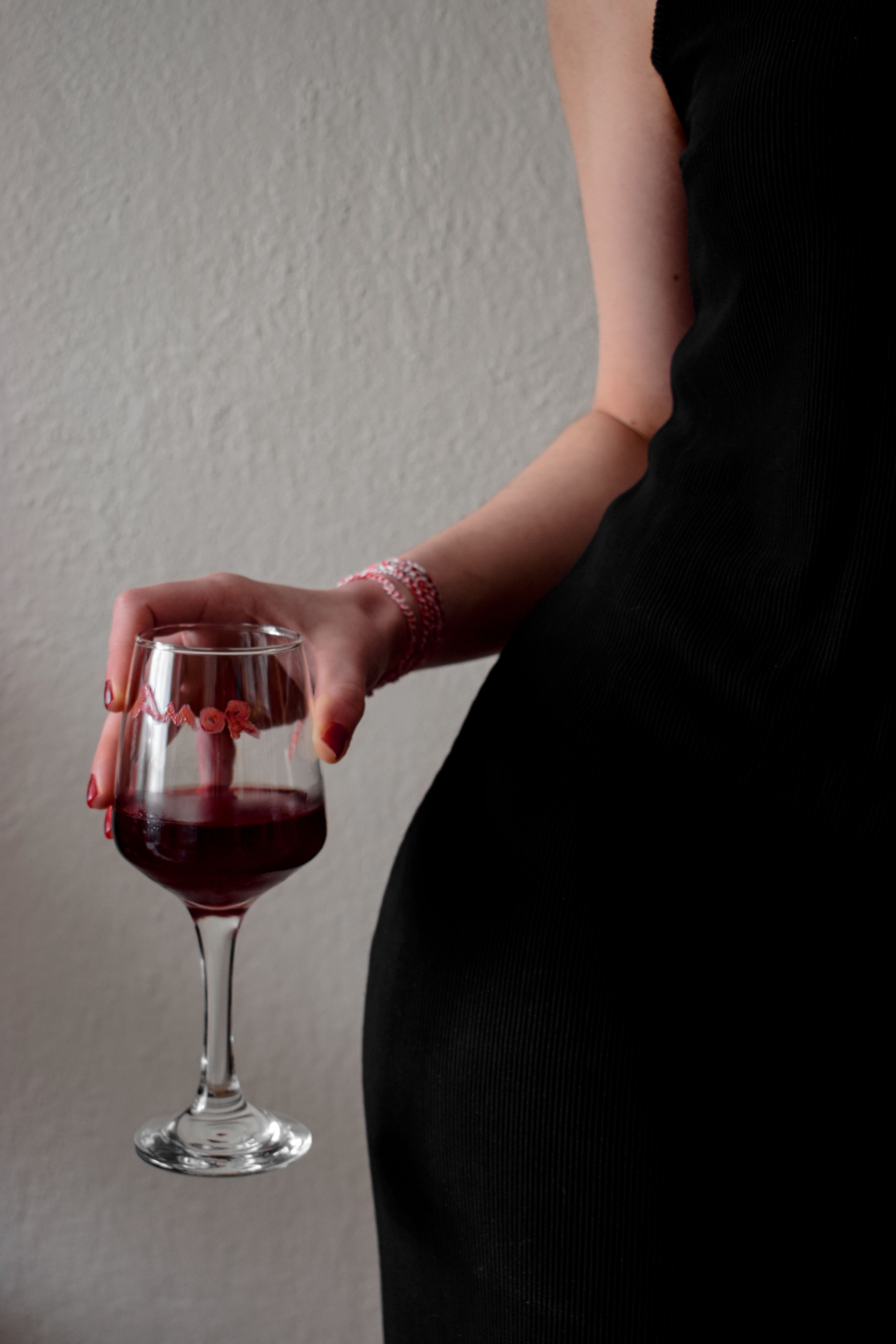 A woman in a black dress holding a glass of wine · Free Stock Photo