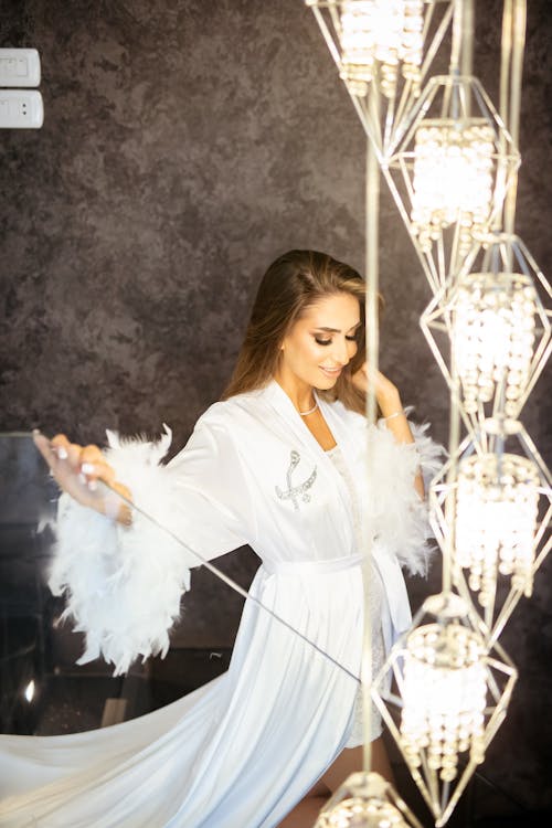 Pretty Blonde Wearing a White Robe with Electric Lights Glowing in the Foreground