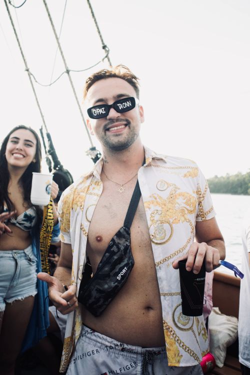 Free Two adults enjoying a lively boat party with drinks, wearing sunglasses and summer attire. Stock Photo