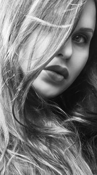 Close-up black and white portrait of a woman with long hair in an artistic style.