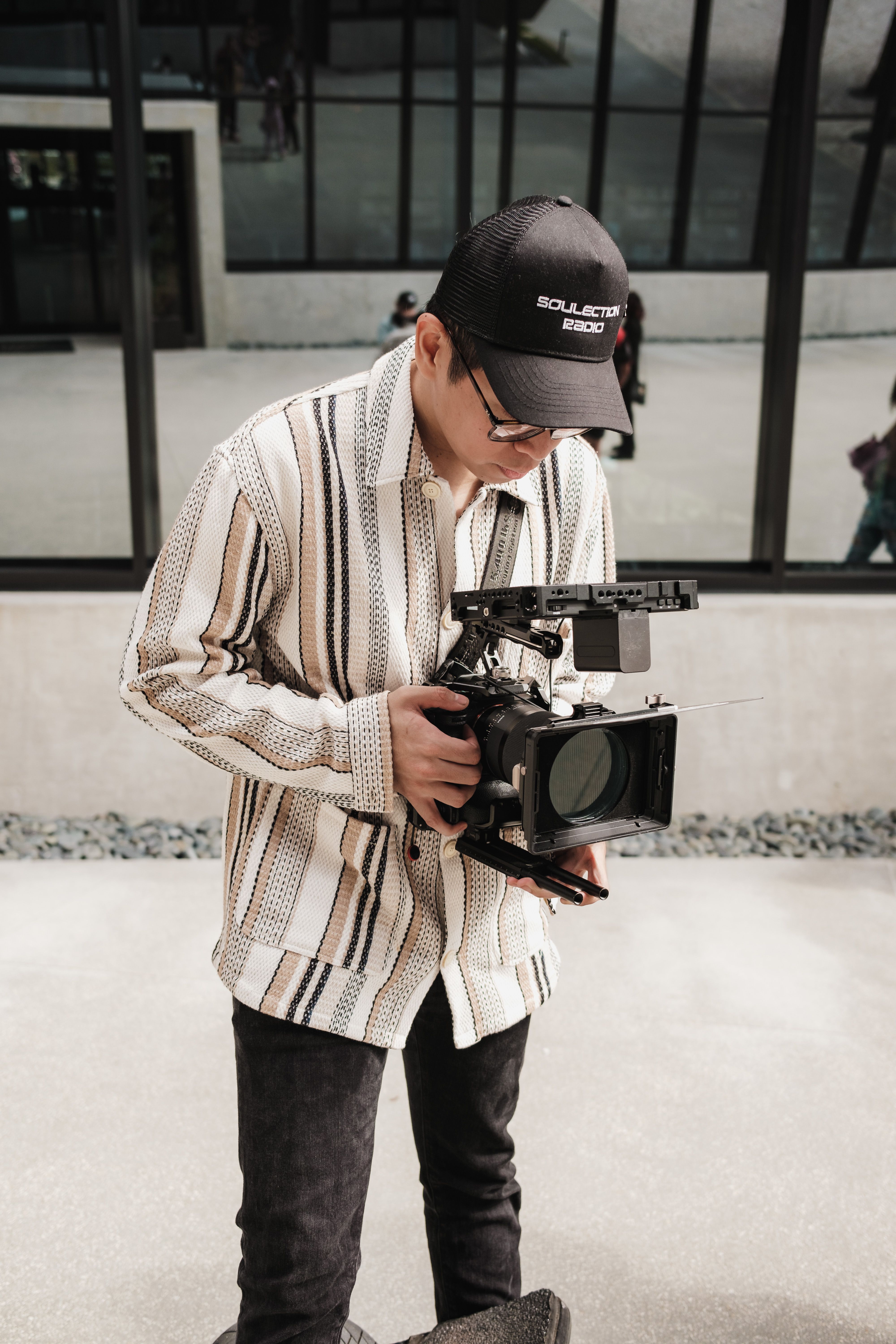 A man in an urban setting focusing on operating a professional camera outdoors.