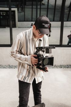 A man in an urban setting focusing on operating a professional camera outdoors.