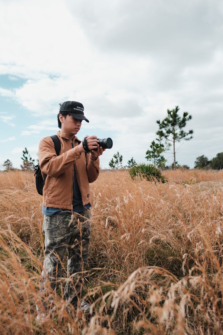 Man In Cap And With Camera On Field