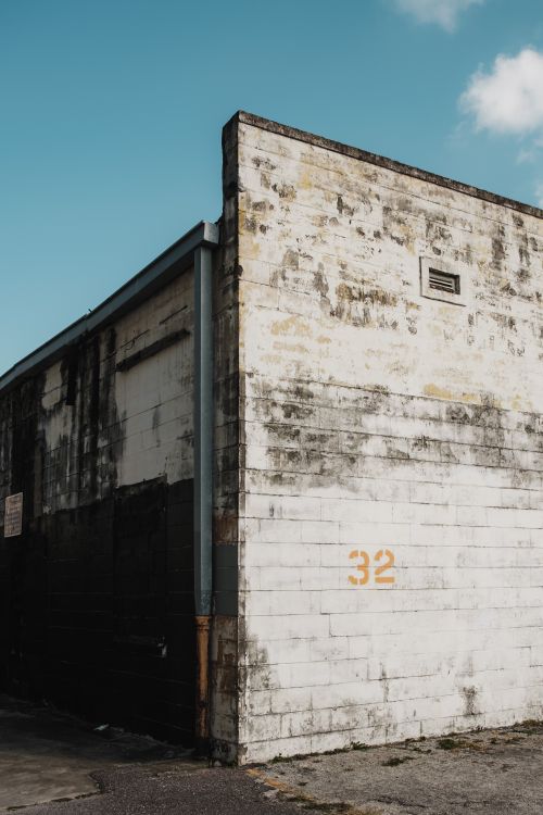 Free Aged structure with peeling paint under a blue sky, showcasing urban decay. Stock Photo