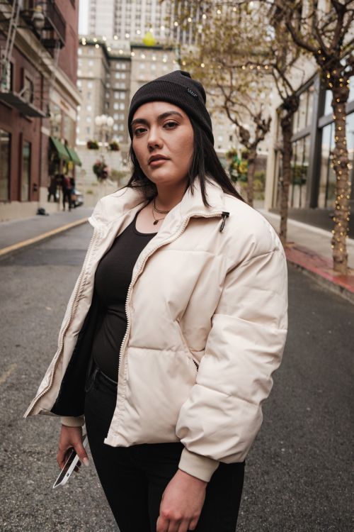 Free Fashionable woman standing confidently in winter outerwear on a decorated city street. Stock Photo