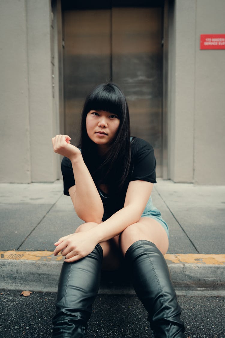 Young Woman Sitting On Pavement On Street