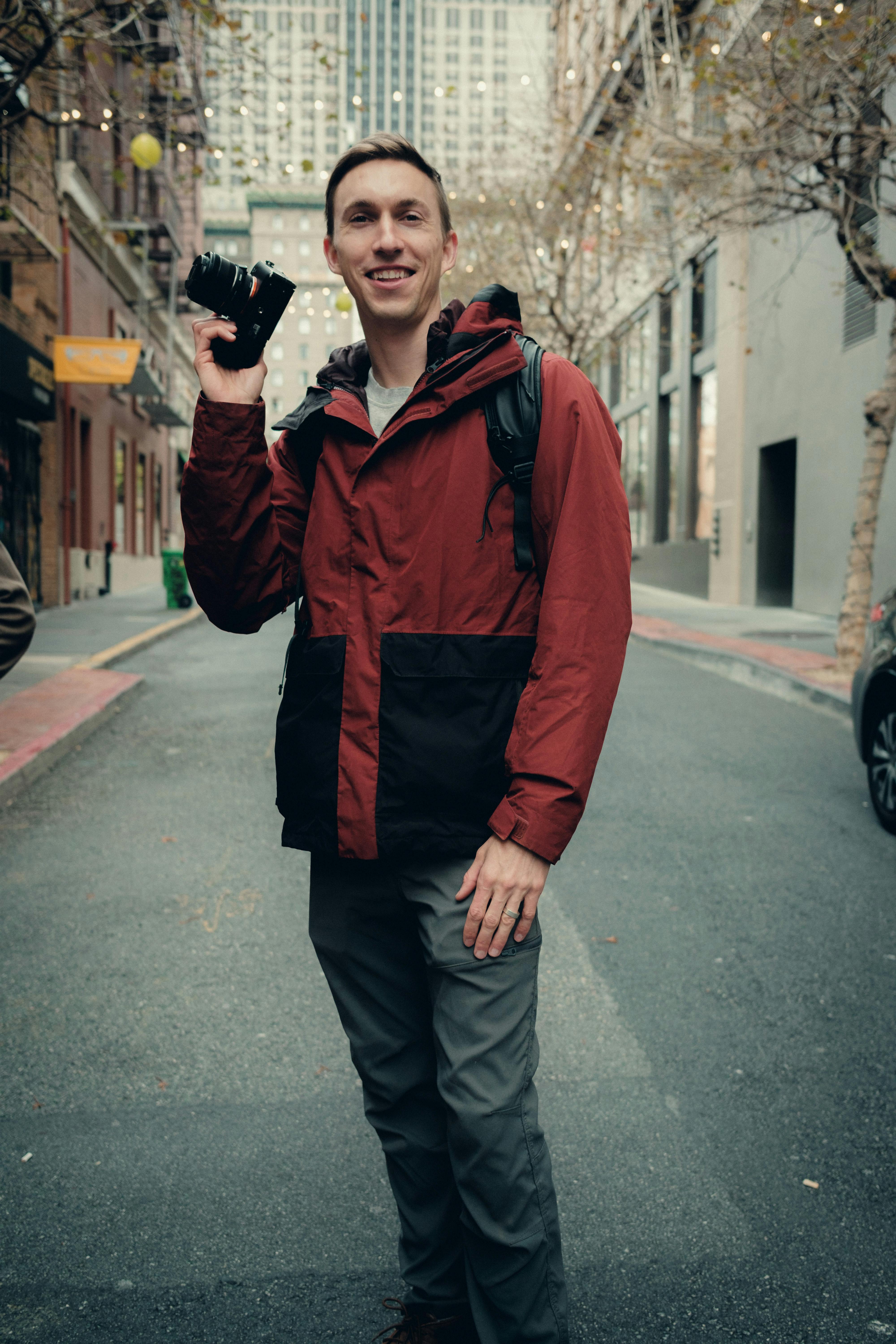 smiling man with camera standing on city street