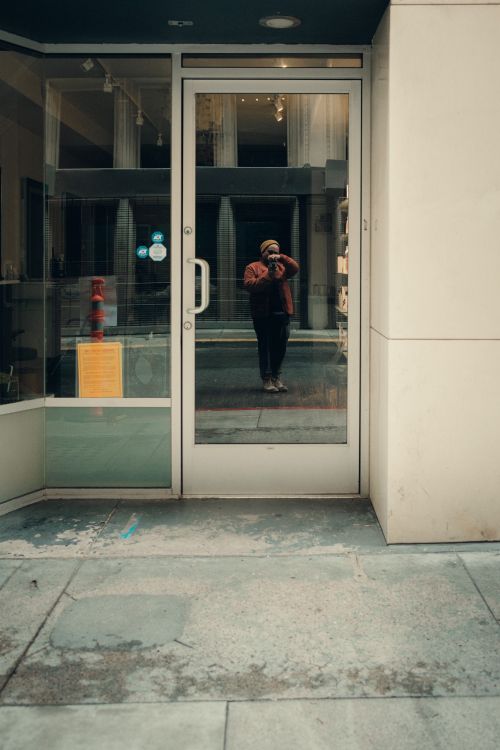 Free Photographer's reflection in a city glass door capturing urban vibes. Stock Photo