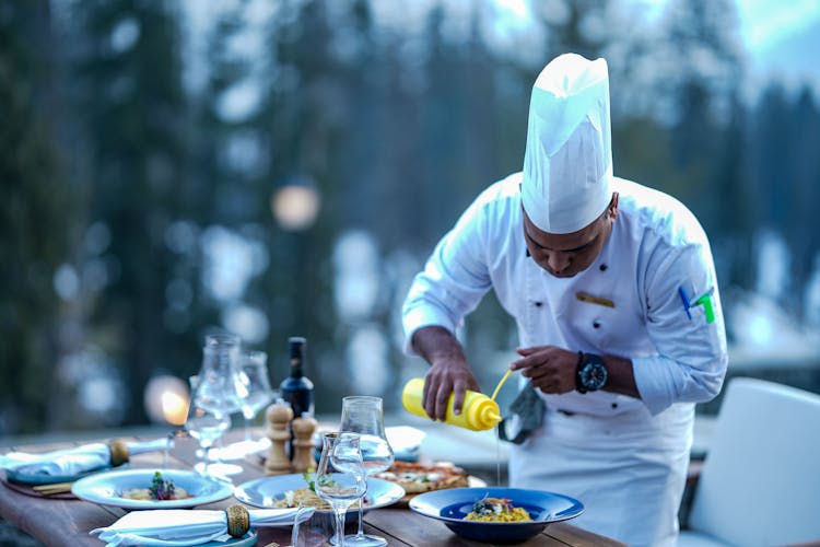 Chef Finishing Meal On Restaurant Table