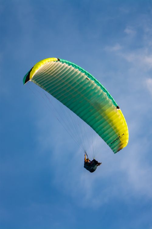 Free Dynamic paraglider soaring through the clear sky, capturing the thrill of flight and freedom. Stock Photo