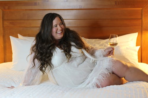 Woman Lying in Bed and Holding a Glass of Wine 