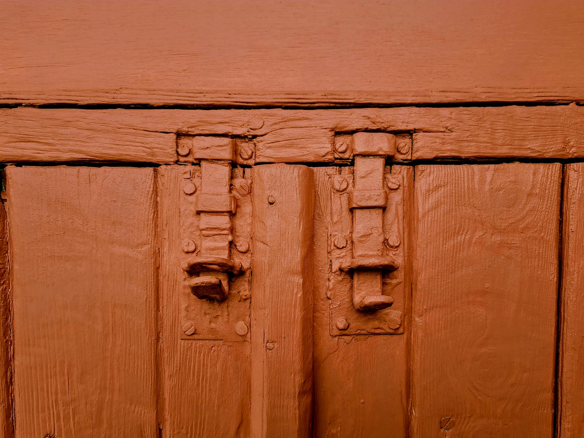 Close-up of a vintage red-painted wooden door with metal latches in Nicosia, Cyprus.