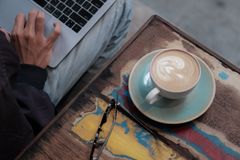 High-angle view of a person working remotely on a laptop with a cup of coffee on a vibrant-colored table.