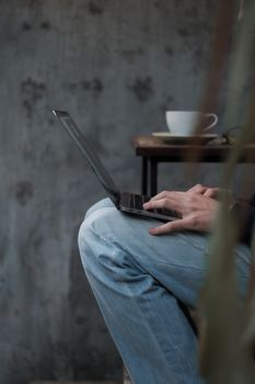 Close-up of a man working on a laptop with coffee cup in a cozy café.