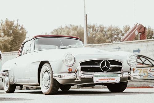 Free Vintage white Mercedes 190 SL convertible displayed outdoors with a backdrop of graffiti art. Stock Photo