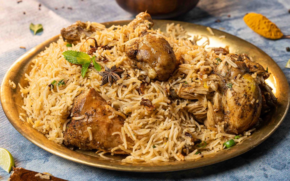 Chicken biryani served on a brass plate with garnishes