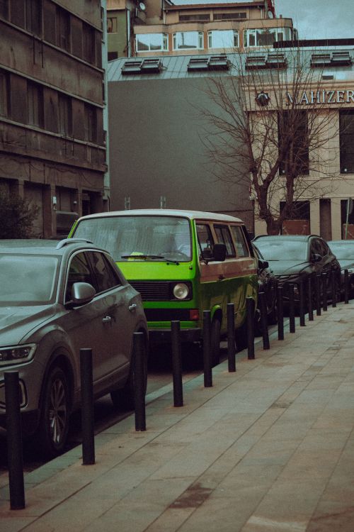 Free A city street scene featuring a vintage green van parked among modern cars, showcasing an urban lifestyle. Stock Photo