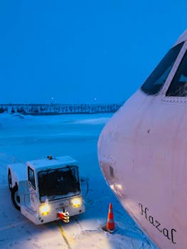 Airplane being towed in snowy Istanbul airport during winter evening.