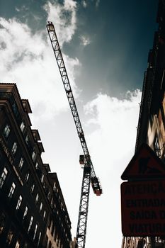 Silhouette of a construction crane between buildings under a vibrant sky.