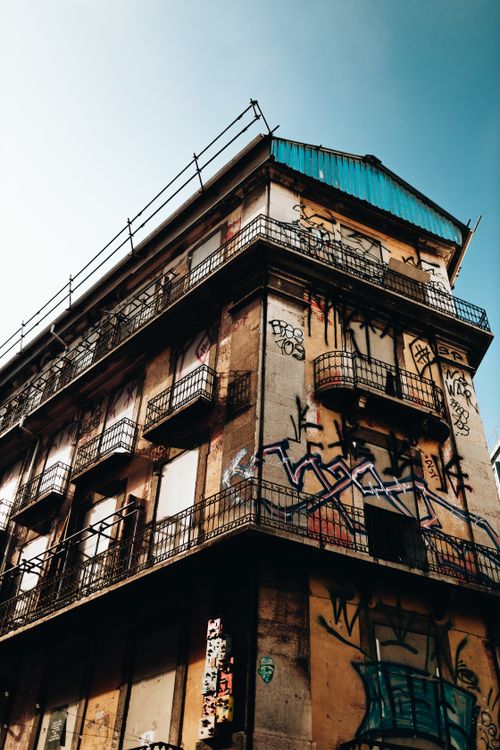 Free Low-angle view of a historic building facade adorned with urban graffiti, showcasing balconies. Stock Photo