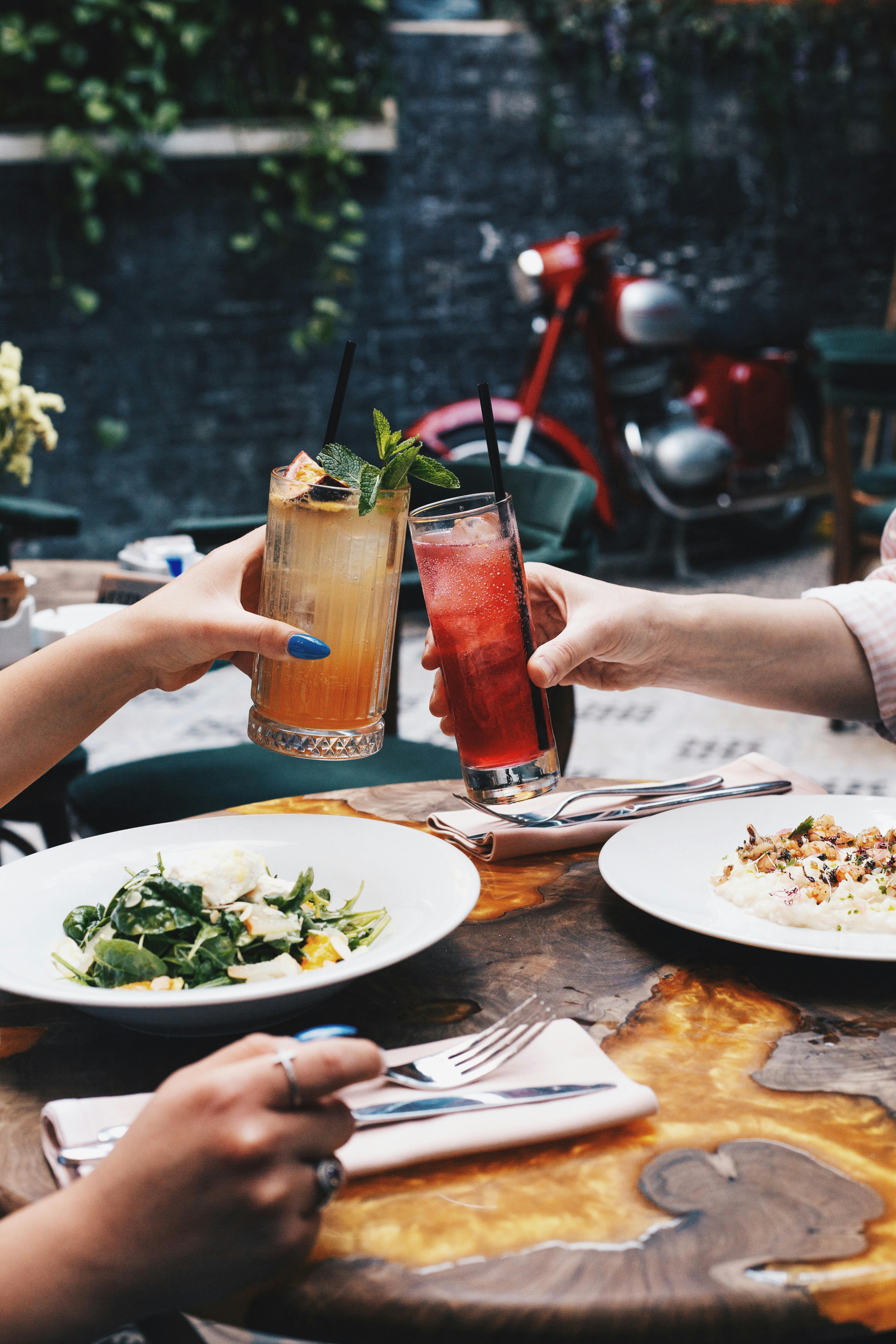 people cheers with cocktails eating in restaurant