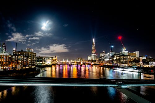 Free Beautiful night view of London's skyline with illuminated bridges and buildings along the Thames River. Stock Photo