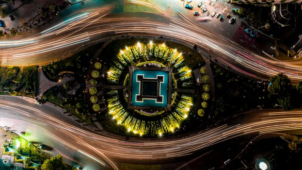 Stunning aerial view of an illuminated roundabout in Lahore, showing vibrant light trails and symmetrical design.