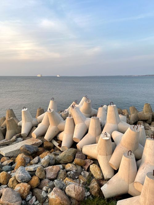 Free Concrete breakwater structures along Tallinn coast with ships on Baltic Sea horizon. Stock Photo