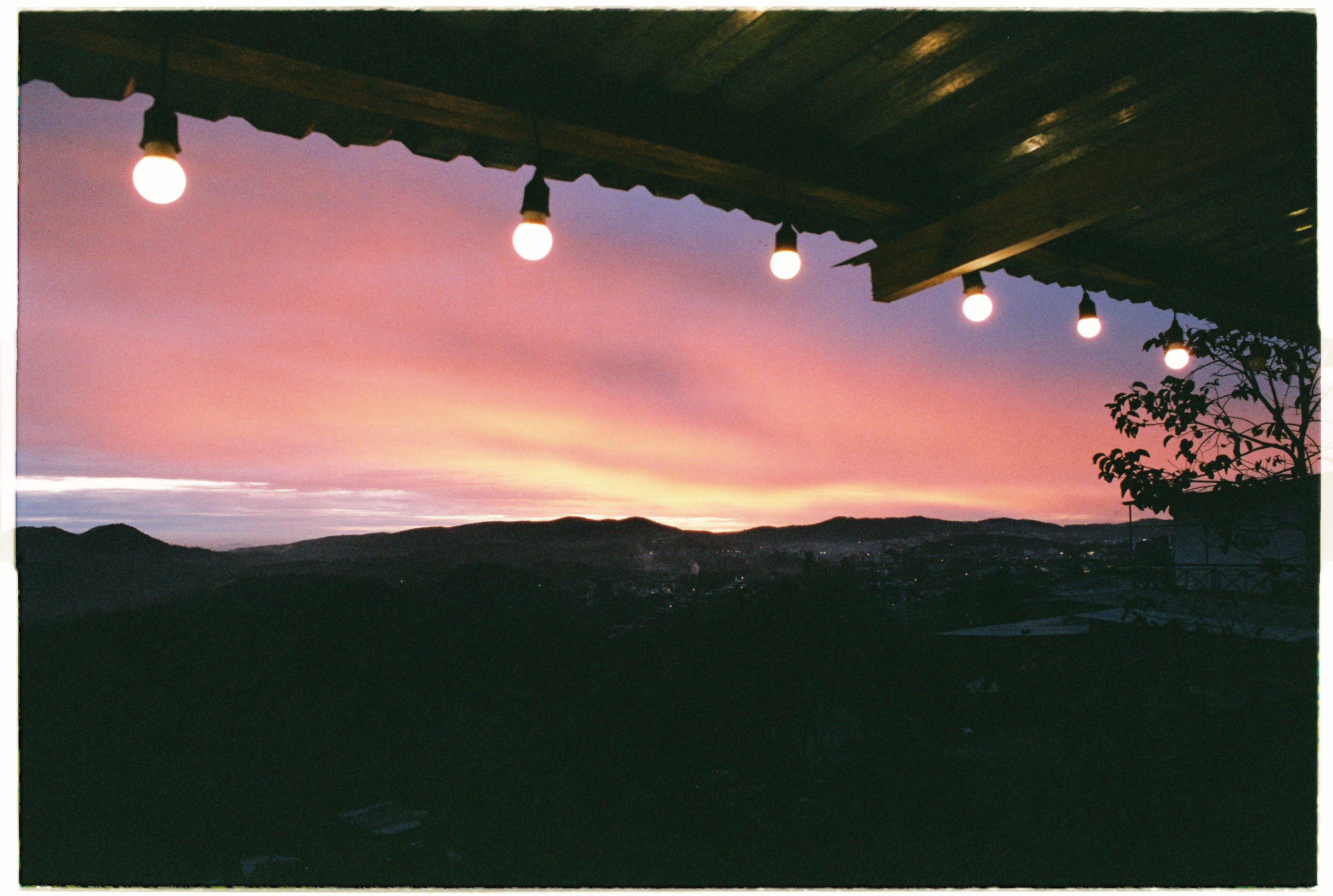 A hotel rooftop terrace at sunset with Signal Hill and the Atlantic beyond