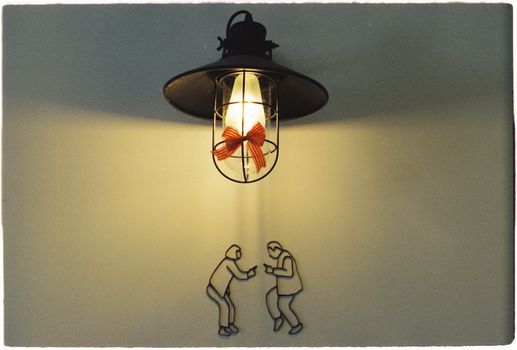 Vintage lamp with light bulb and art figures on a wall creates a unique aesthetic.