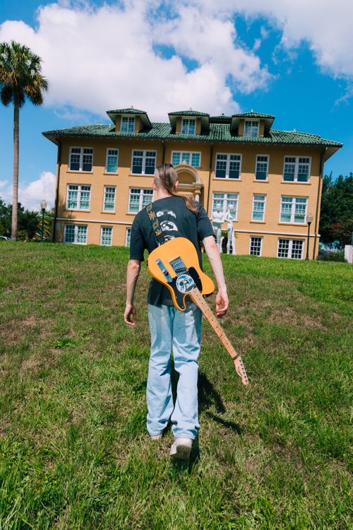 Free A man carrying a guitar walks towards a historic building in Orlando, Florida. Stock Photo