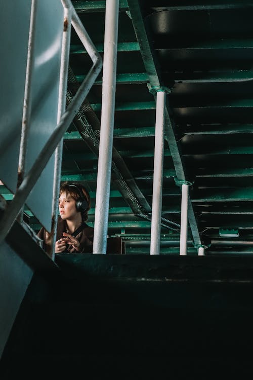 A Young Person Wearing Headphones and Sitting in an Industrial Building 