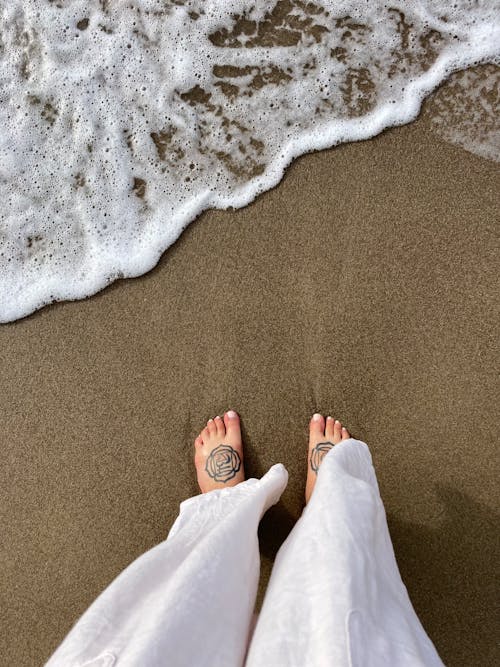 Woman with Tattoos on Her Feet Standing on the Beach 