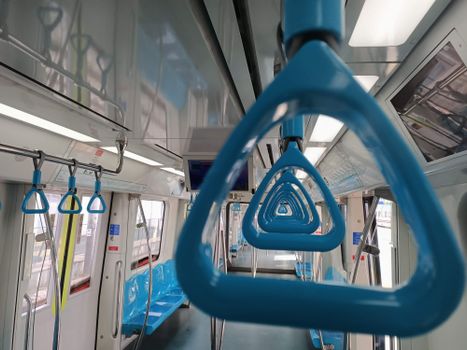 A close-up view of blue grab handles in a modern subway train interior showcasing contemporary design.