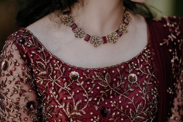 a beautiful necklace on woman's neck wearing red indian dress