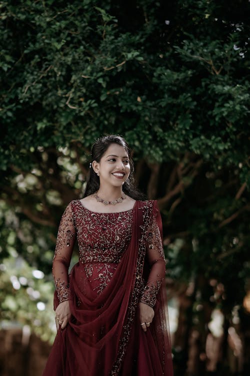 Young Woman Wearing a Traditional Burgundy Dress and Smiling 