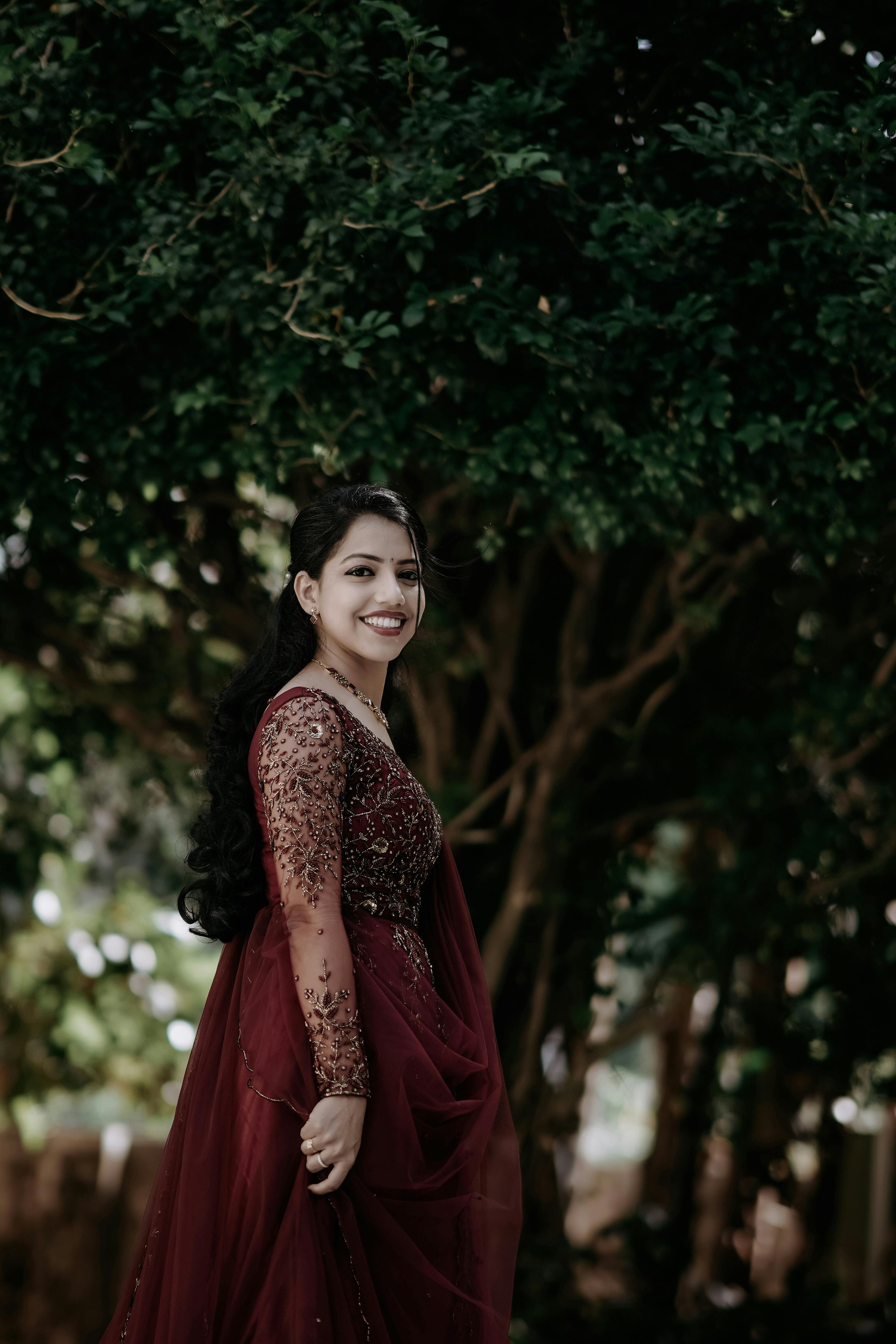 free photo of woman in traditional dress posing under tree