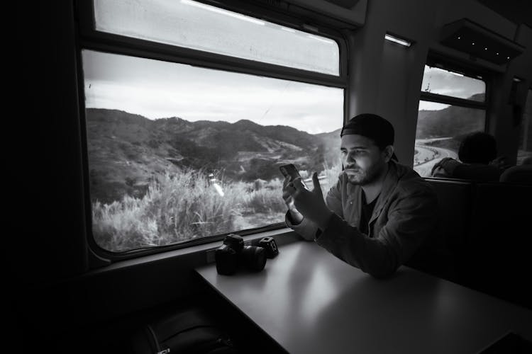 Man Sitting At The Table In A Train And Using His Phone 