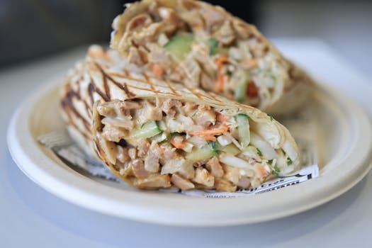 Close-up of a chicken wrap with fresh vegetables on a plate.
