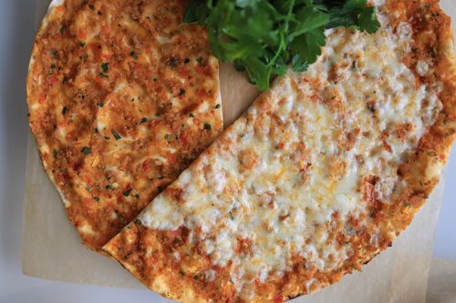 Free Close-up of a tasty cheese and herb pizza on parchment paper with fresh parsley. Stock Photo