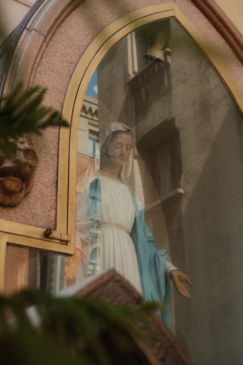 Free Statue of Madonna visible through a reflection in church glass. Spiritual symbolism. Stock Photo