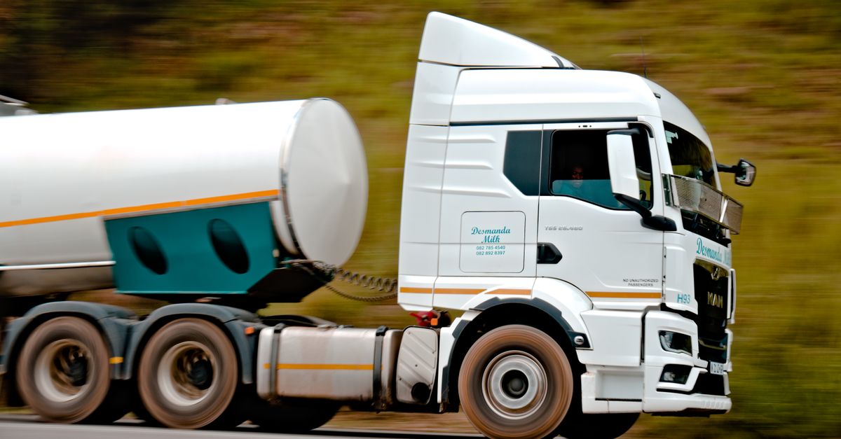 Close-up of a fast-moving white tanker truck on a highway, capturing motion and speed.