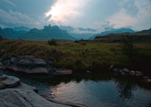 Free A serene mountain landscape at dawn with a calm water body reflecting the sky's hues. Stock Photo