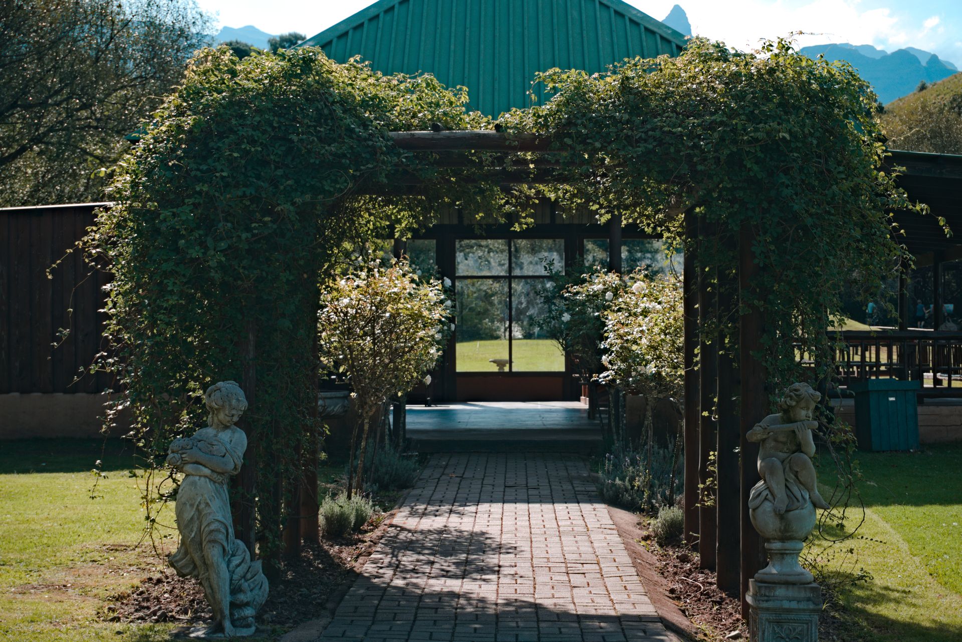 Picturesque garden entrance adorned with stone statues and lush greenery, offering a serene atmosphere.