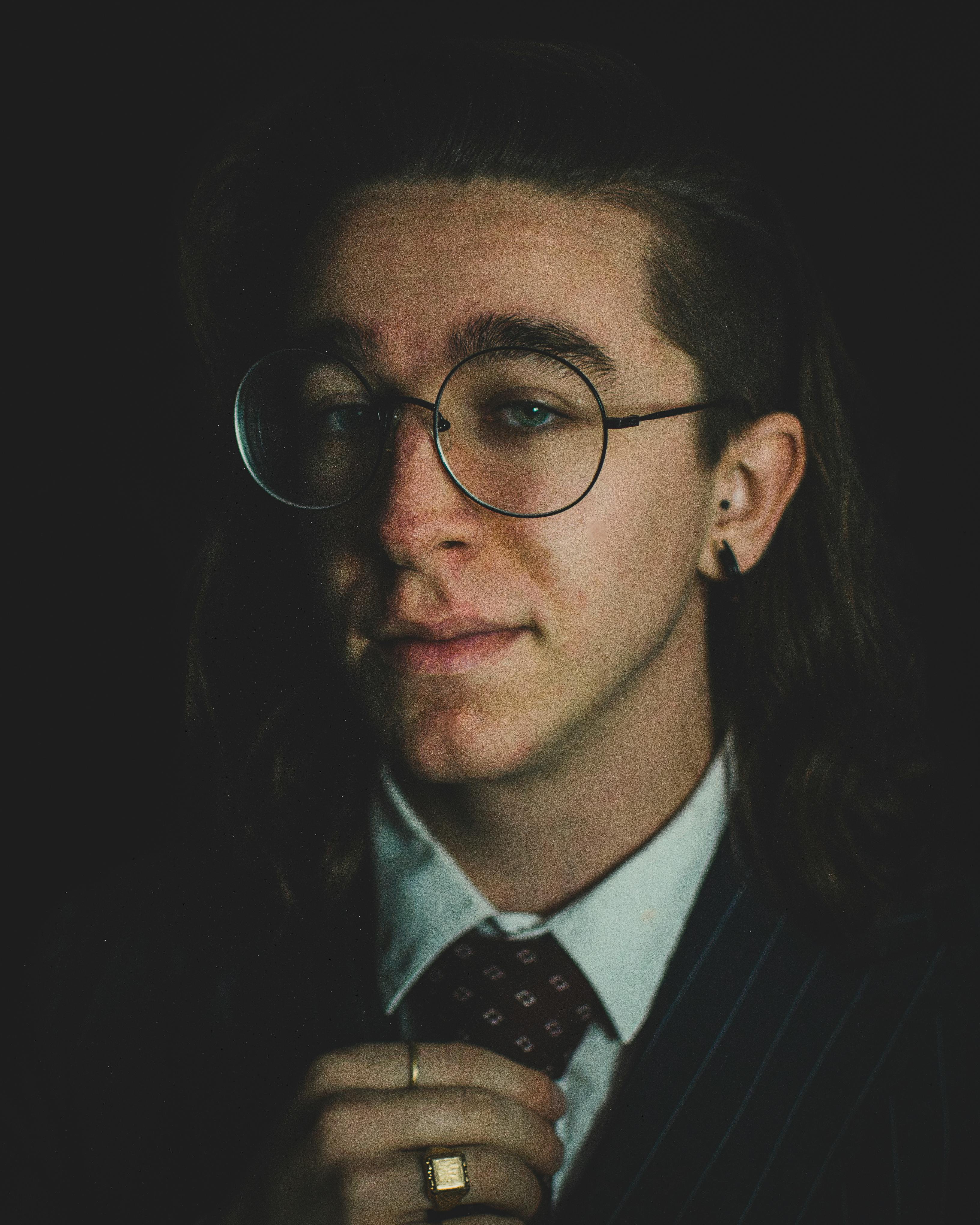 A sophisticated portrait of a young man with eyeglasses, exuding style and confidence.