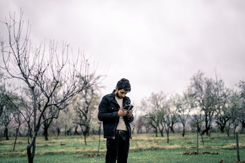 Man Standing in Winter Orchard Playing with Drone