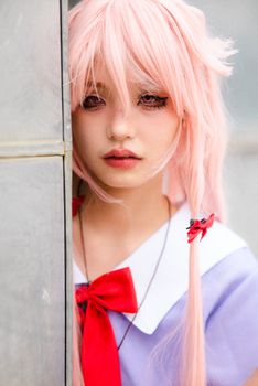 Vibrant anime cosplay costume featuring a pink wig and red bow on a young woman.