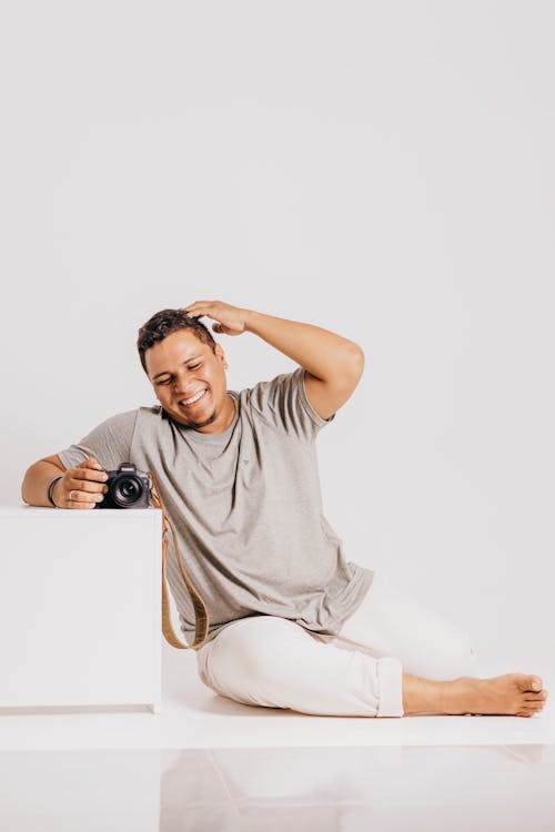 Laughing Man Sitting on Floor by White Box in Studio