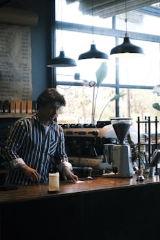 A barista prepares coffee in a modern café, showcasing an inviting and stylish interior.