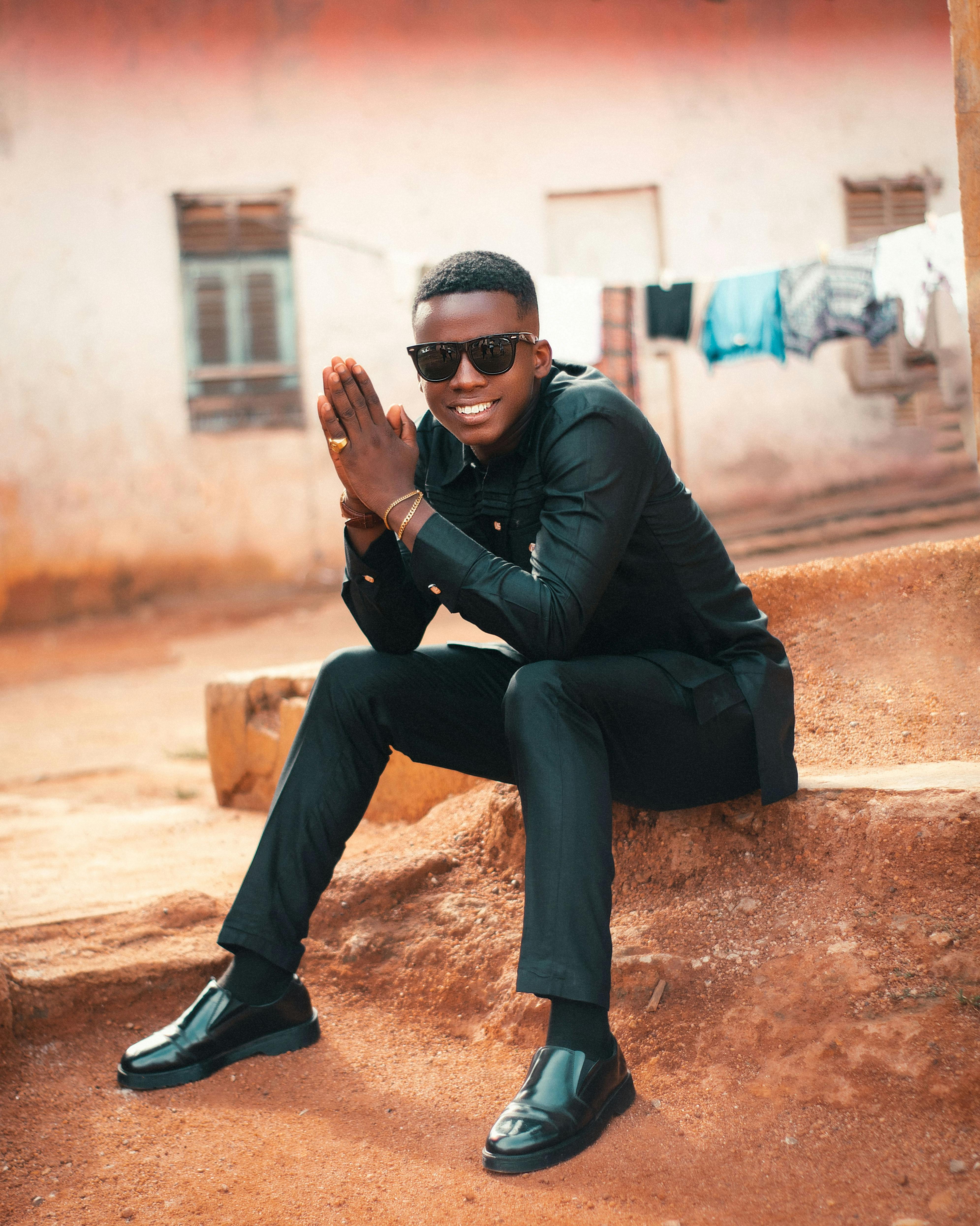 A fashionable young man in Kumasi, Ghana, dressed elegantly and posing confidently outdoors.